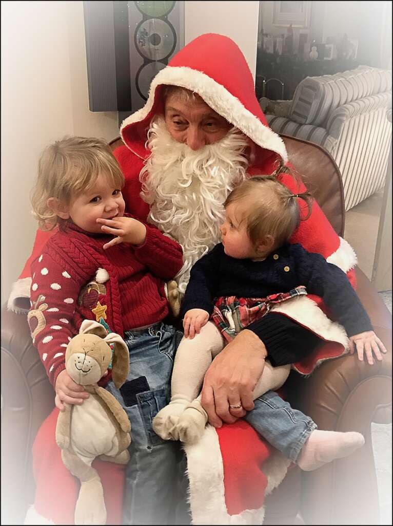 Stan dressed as Santa with his grandchildren.